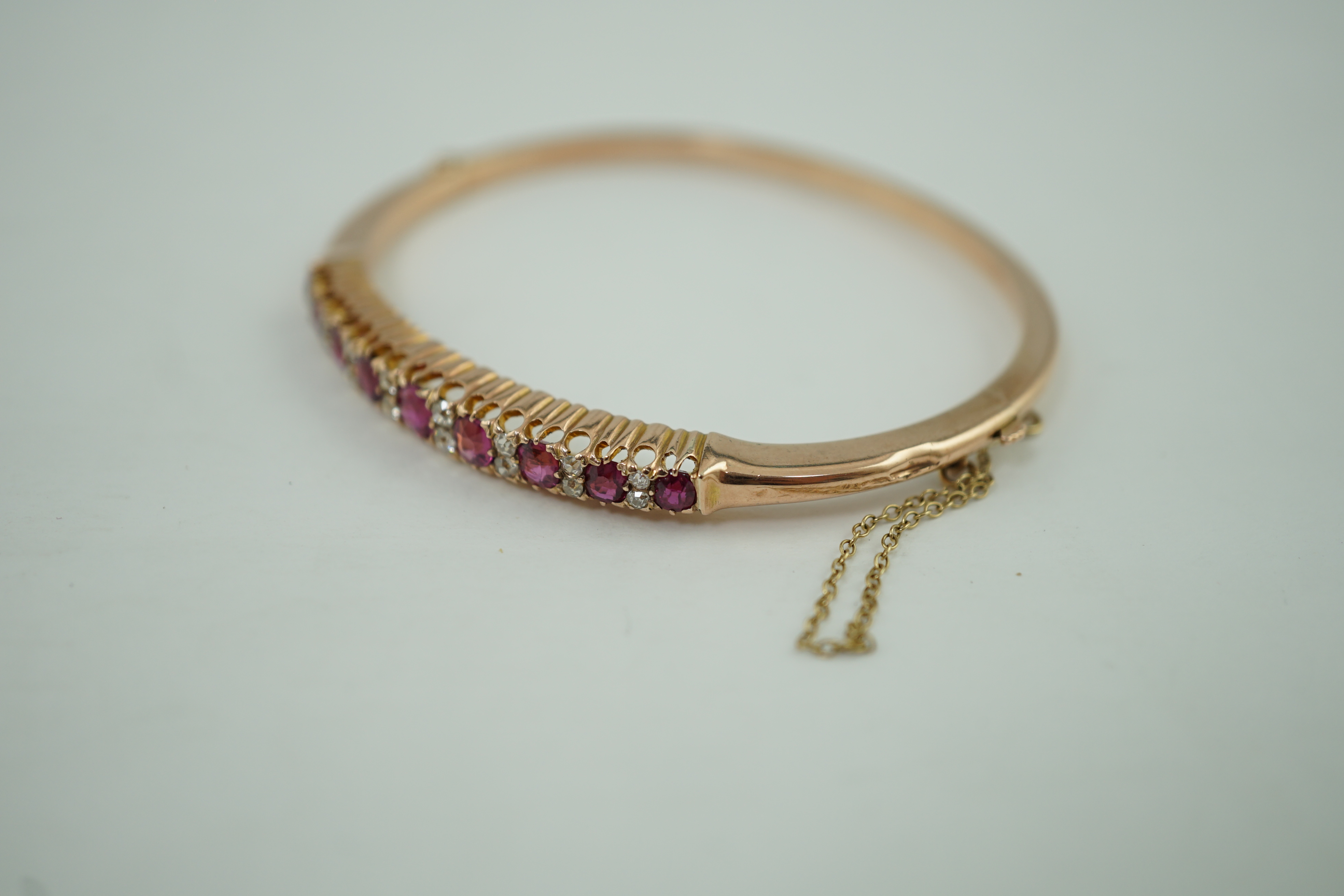 An Edwardian style gold, ruby and diamond cluster set hinged bangle